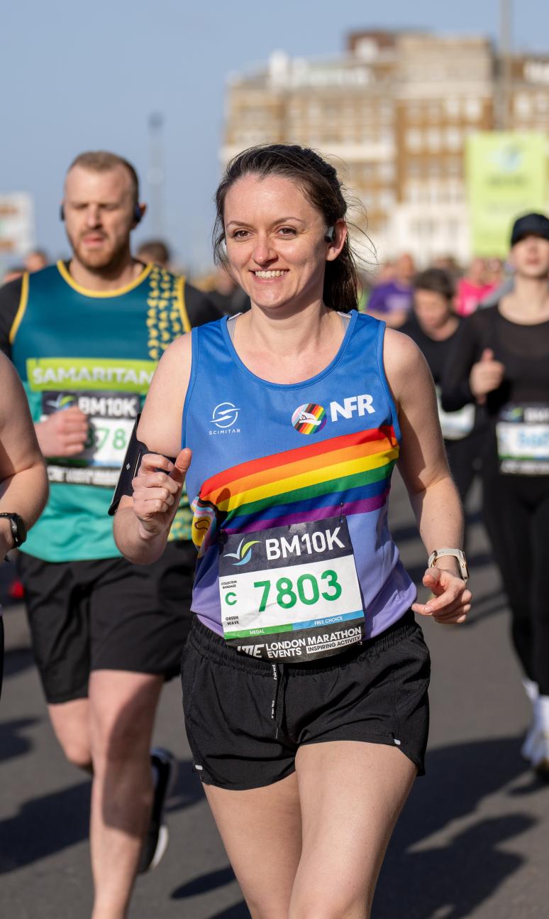 Two people complete in the brighton and hove 10k wearing rainbow vests.