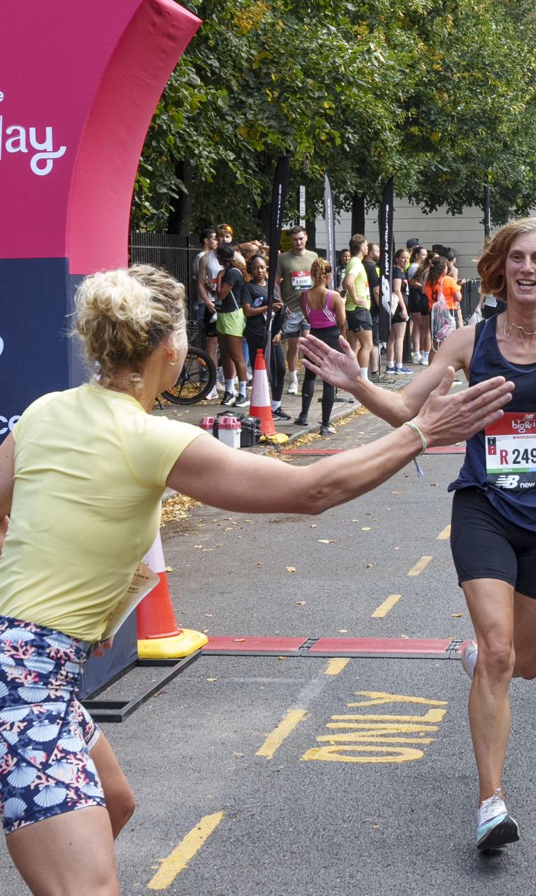 A woman crossing the finish line of the Big Relay tags in her team member to do the next leg of the race.