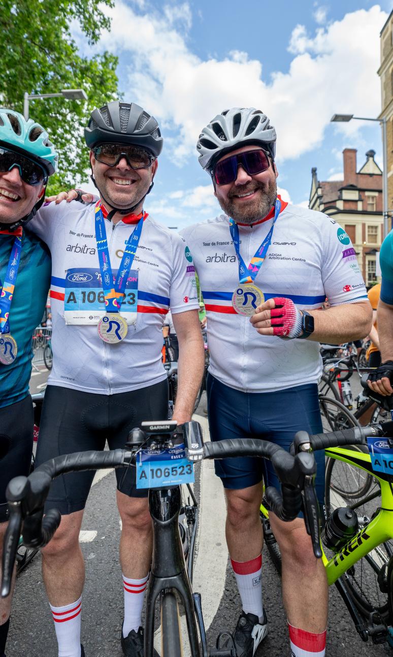 Four men with bikes, smiling and wearing ride london medals