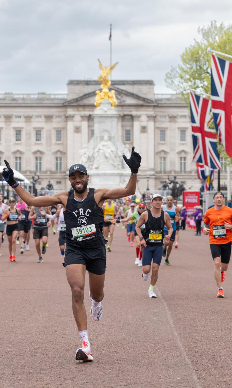 Person approaching the finish line with arms in the air. Multiple runners behind them. 