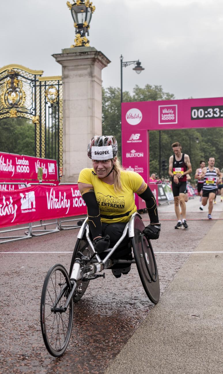 A women crossing the finish line in a racing chair