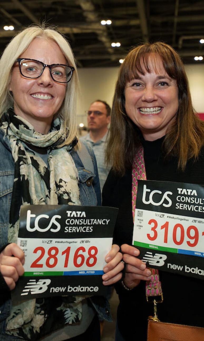 Two participants pose with their running numbers at the TCS London Marathon Running Show