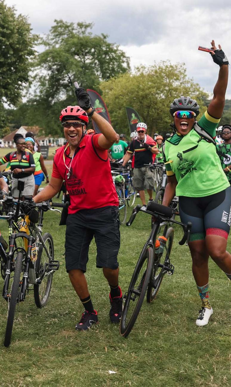 Riders jump for joy in a park during Black Unity Bike Ride