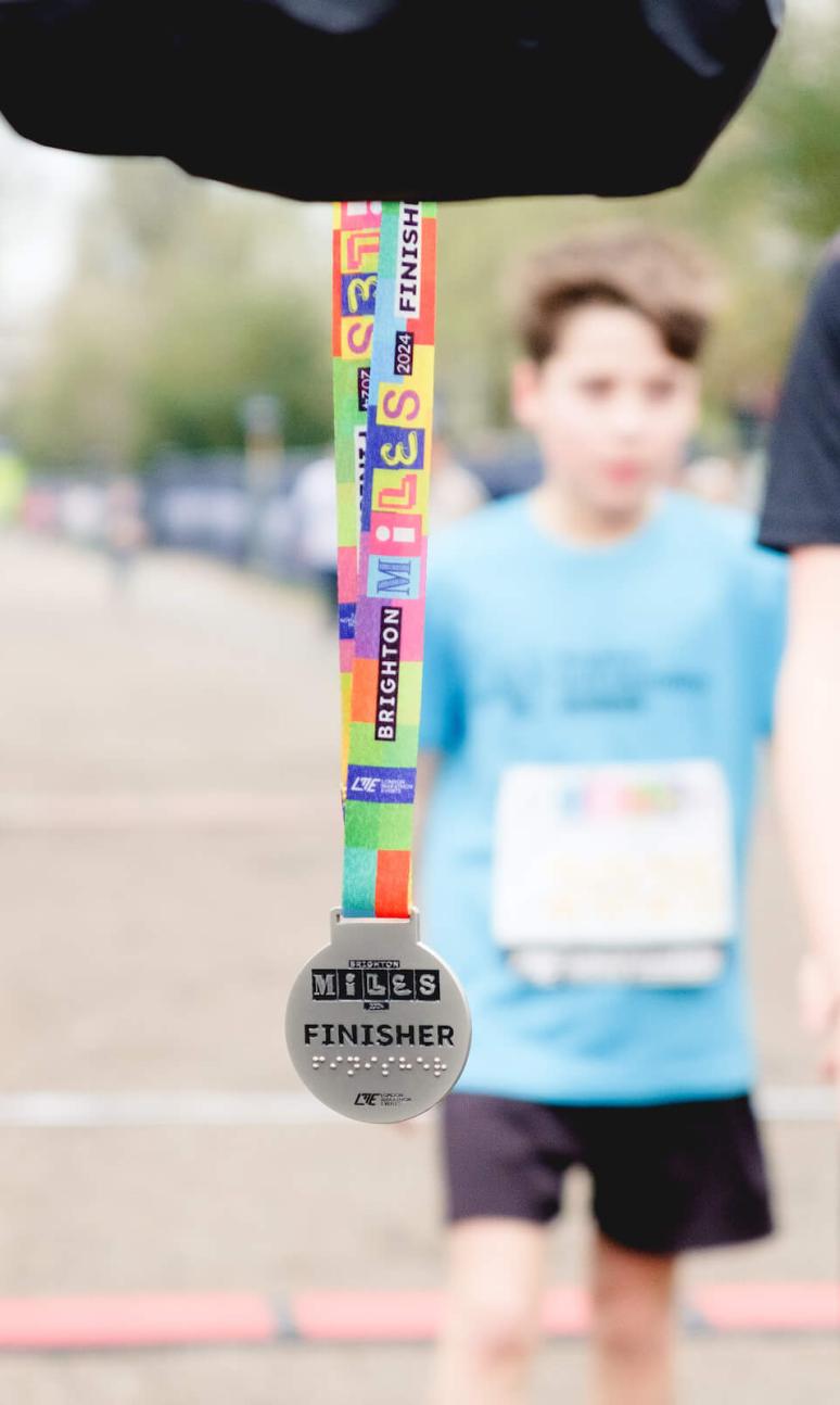 A photo of the Brighton Miles medal in front of the finish line