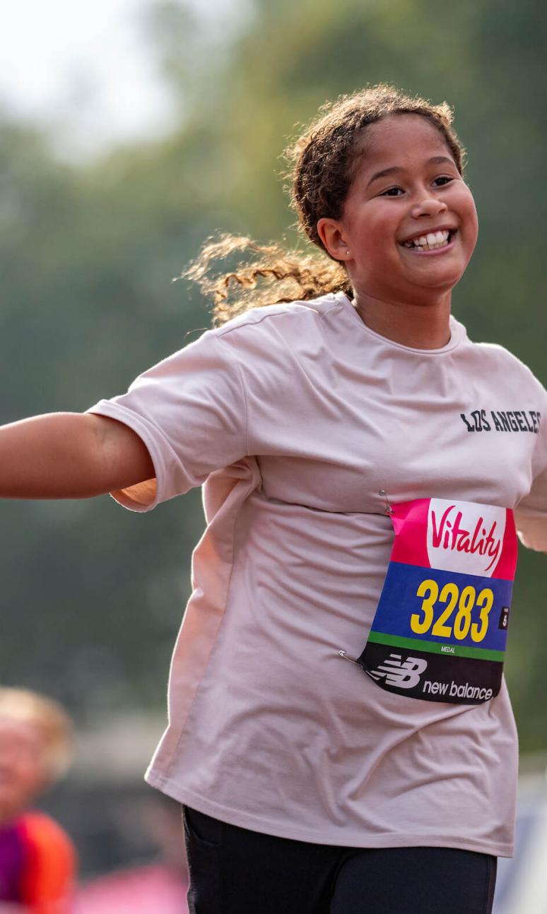 A young girl smiles with her hands out as she runs the Vitality Westminster Mile