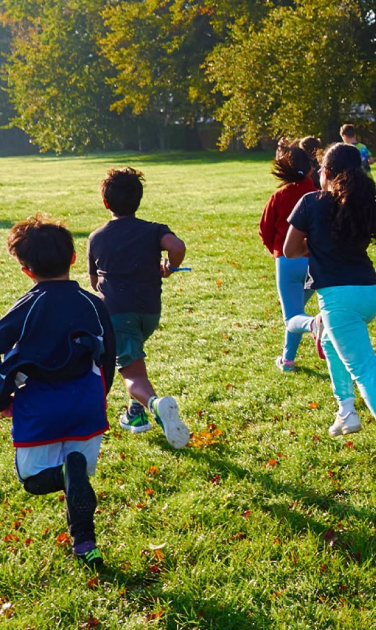 Children running into the sun in a park during junior parkrun