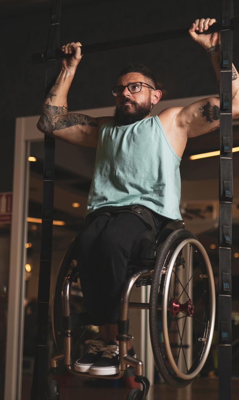 Wheelchair user doing a pull up in the gym