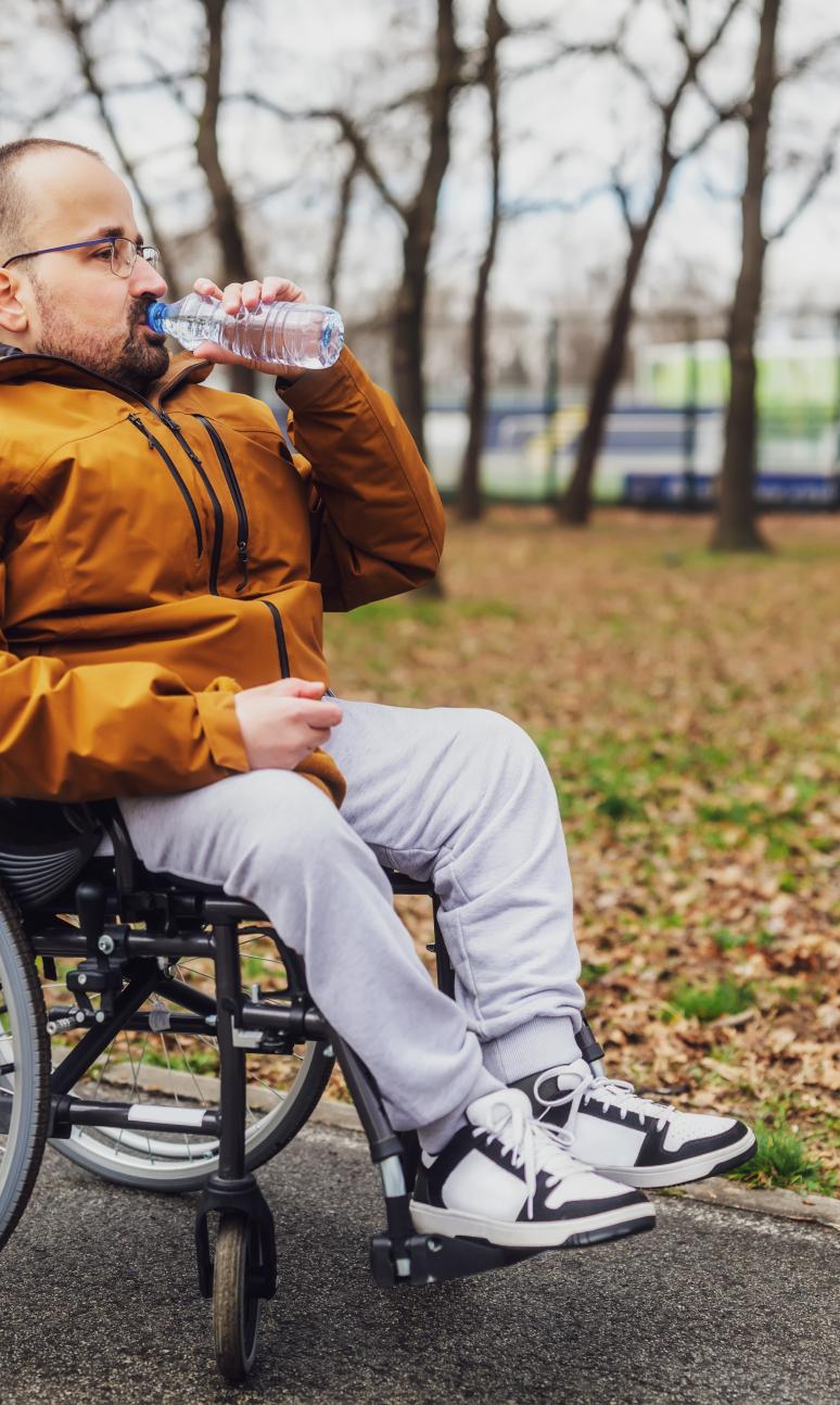 Wheelchair user stops in the park for a drink of water