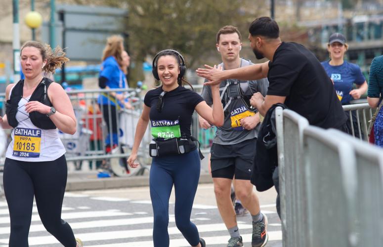 Person running with headphones on high-fiving a spectator hand