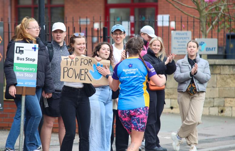 Person holding up a sign saying "tap for power" and runner tapping the sign