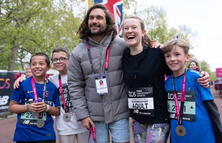 2 adults and 3 children stood next to each other pausing for a photo with their medals around their necks