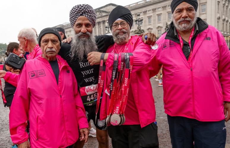 A participant poses with volunteers at the finish line outside Buckingham Palace following The Vitality London 10,000, Sunday 22nd September 2024.