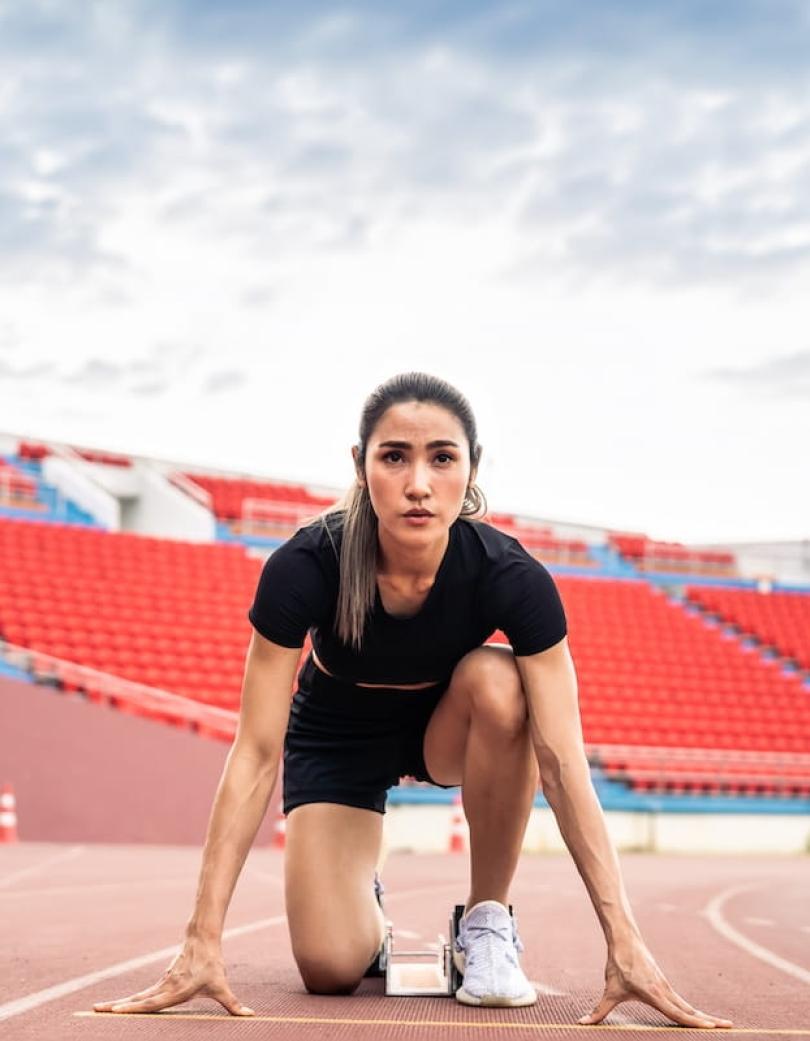 Woman crouches at the start line of a race track