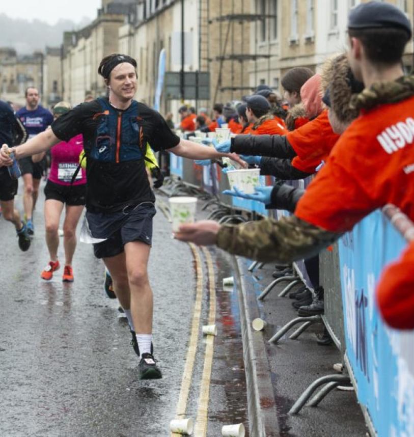 A runner gives high fives to marshals as he runs down the street.