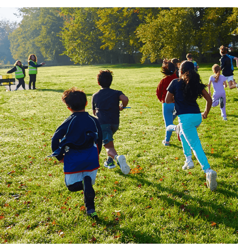 Children running into the sun in a park during junior parkrun