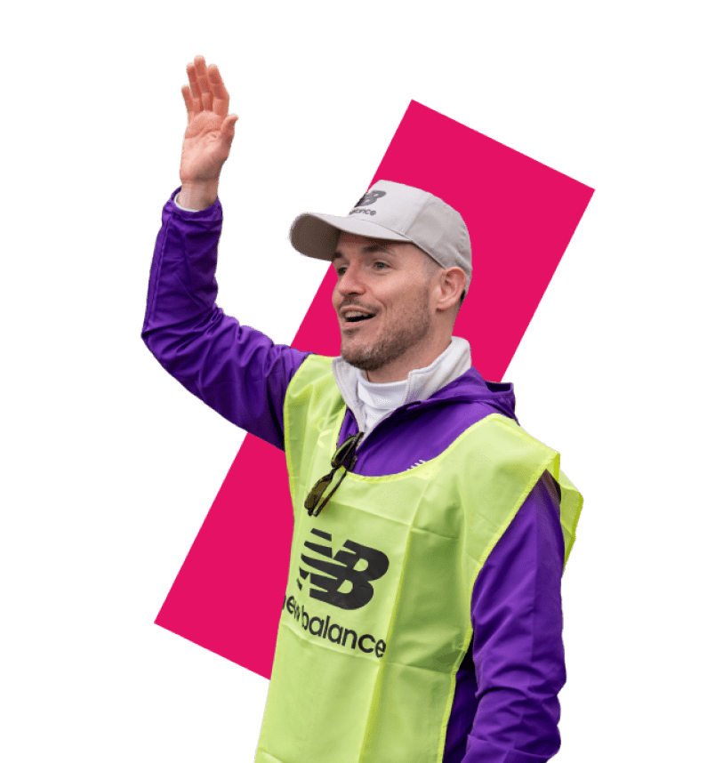 A volunteer with a New Balance tabard on with his hand in the air