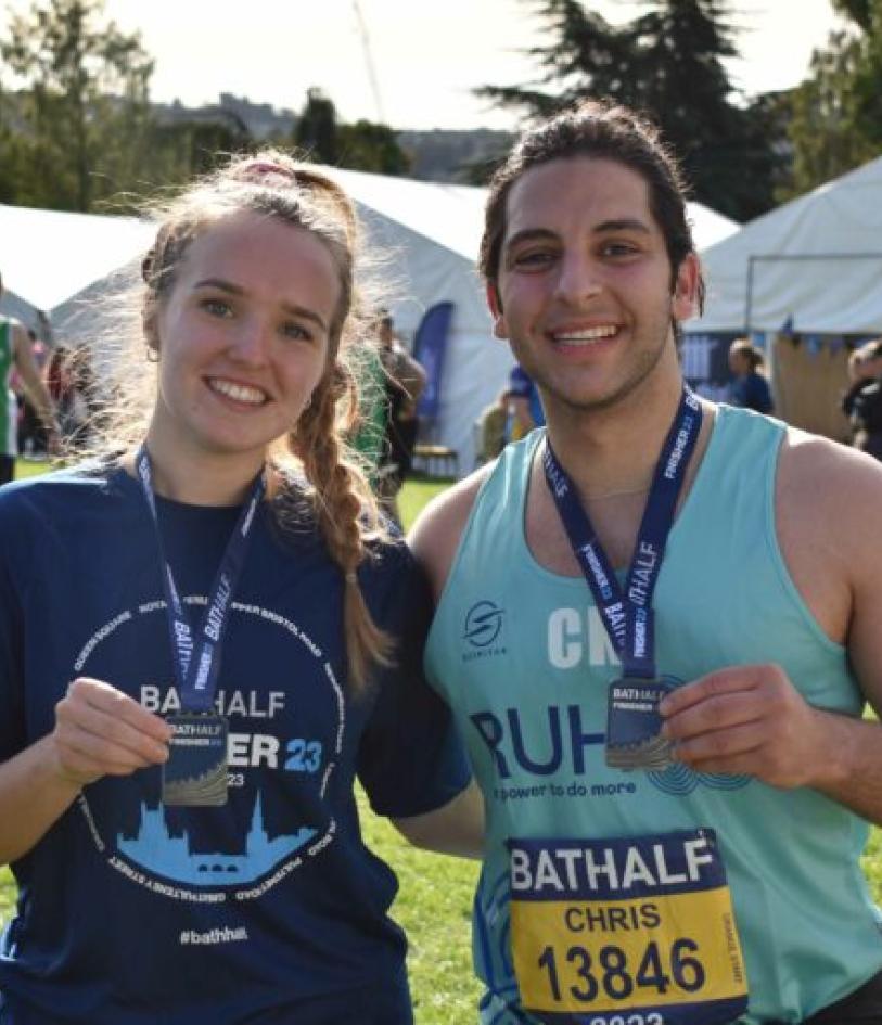 Two runners smile at the camera holding their medals after their event