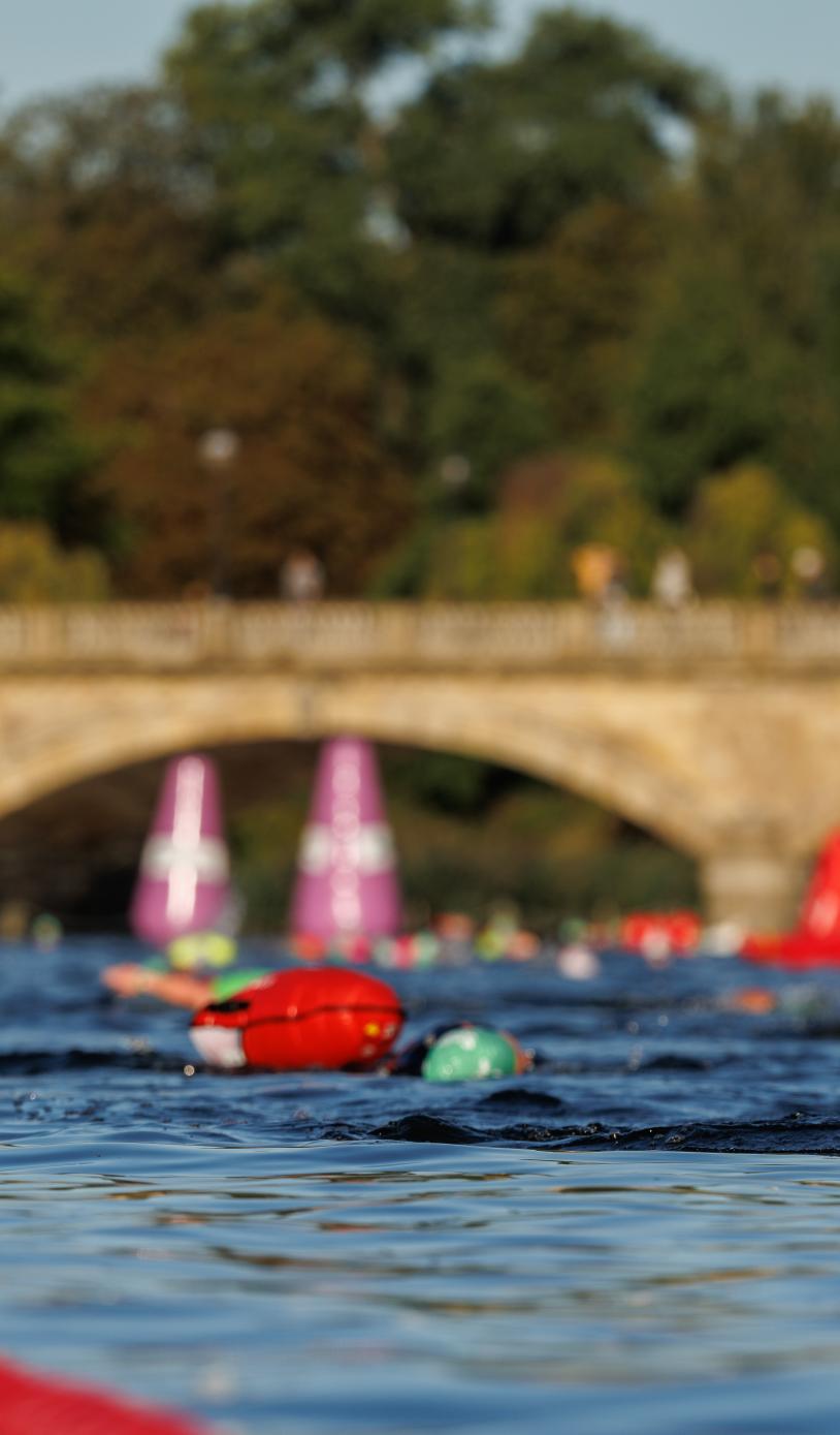 Two Swimmers swim along the swim serpentine route with a bridge in the background.