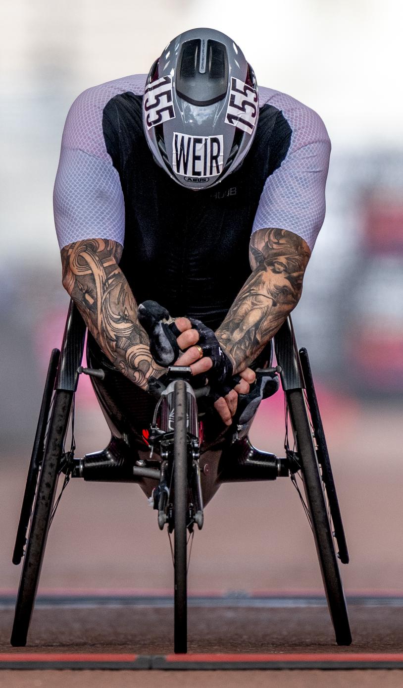 David Weir crossing the finish line lent over the front of his wheelchair