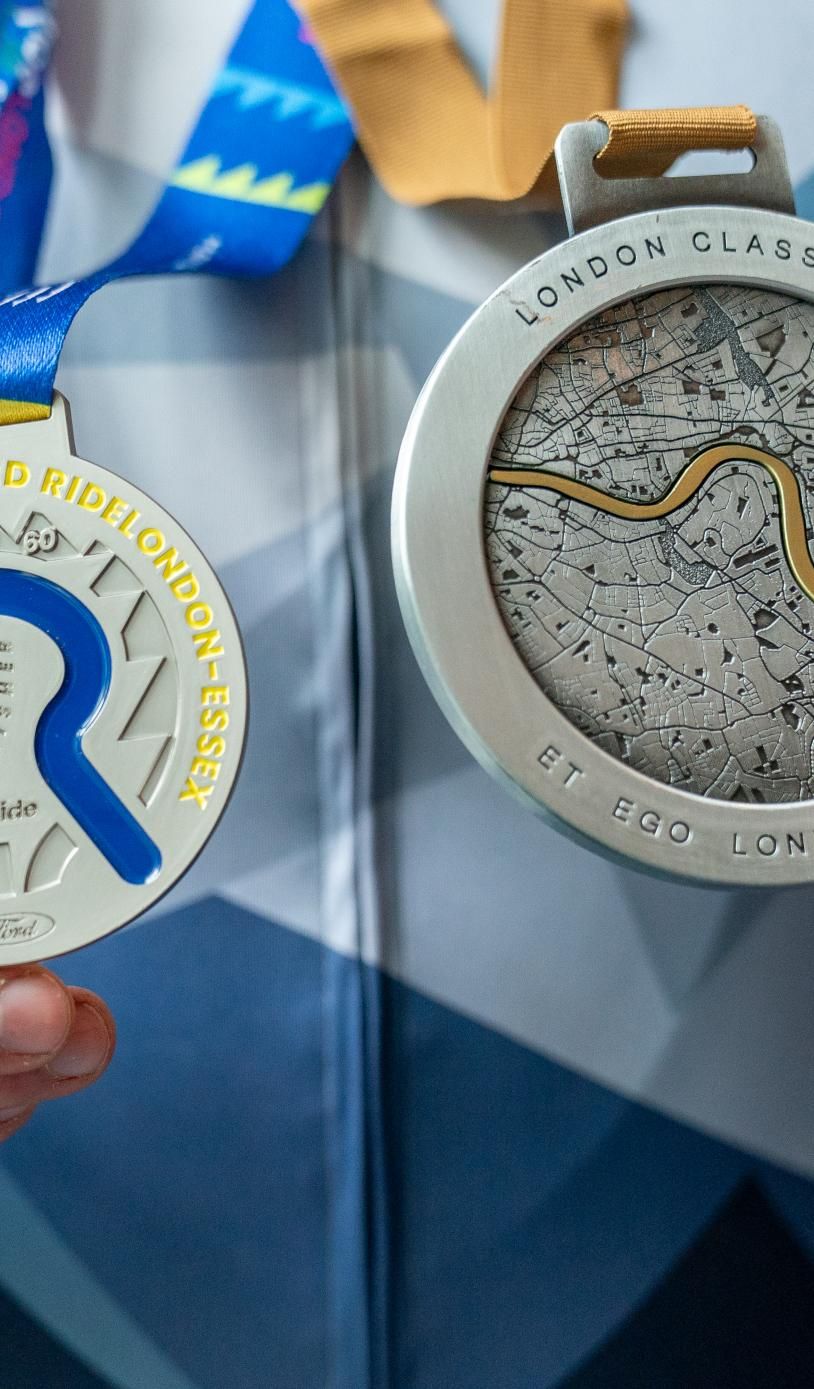 A person holding a London Classics and a RideLondon medal