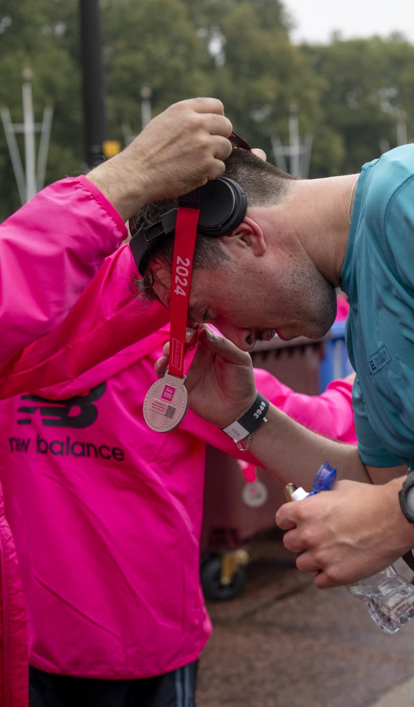 volunteer puts a finisher medal around a runners neck