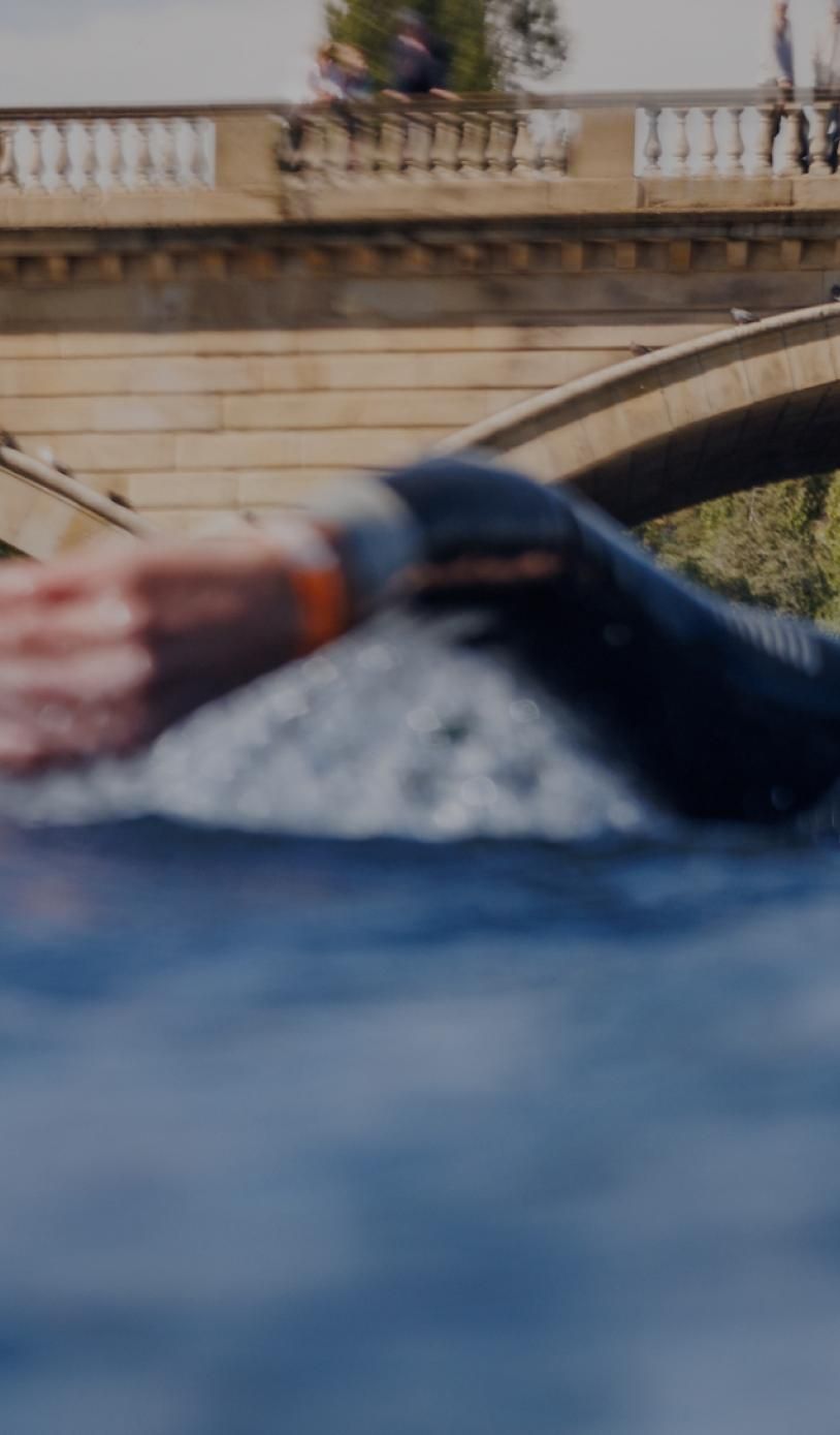 A swimmer shot from water level in front of the Serpentine bridge