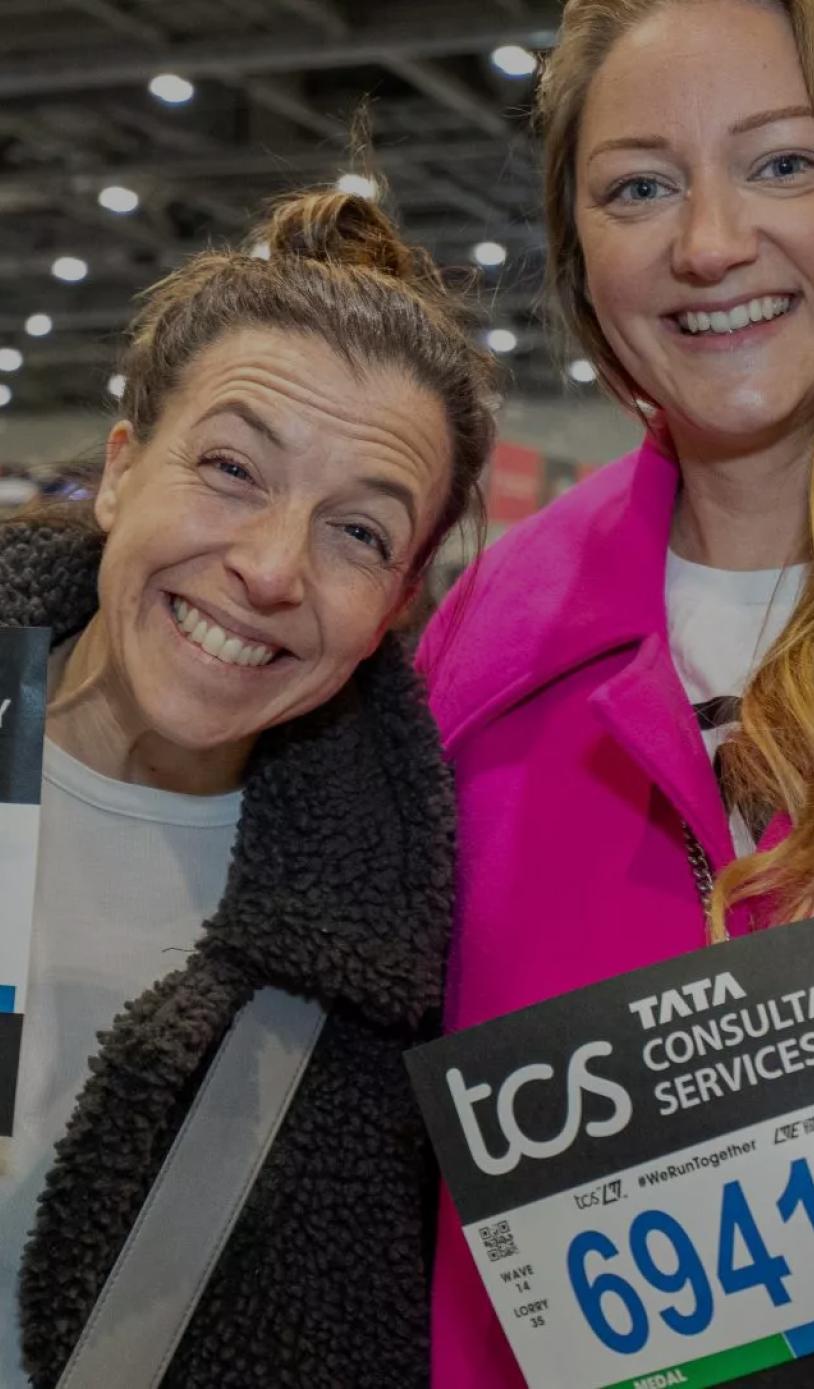 Two participants pose with their running numbers at the TCS London Marathon Running Show