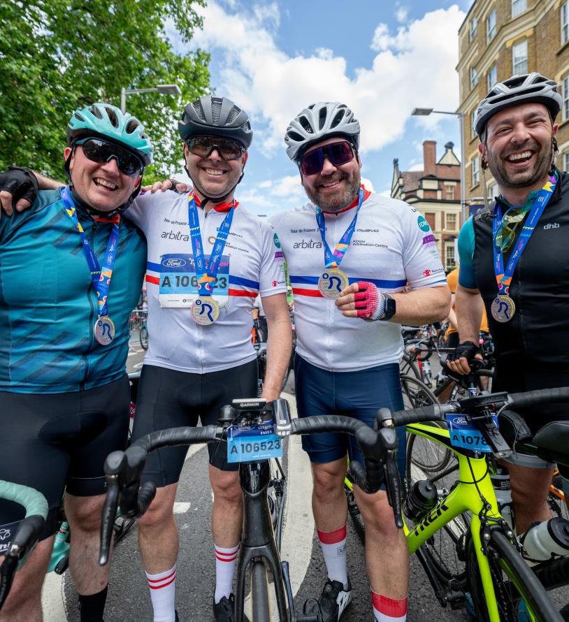 Four men with bikes, smiling and wearing ride london medals