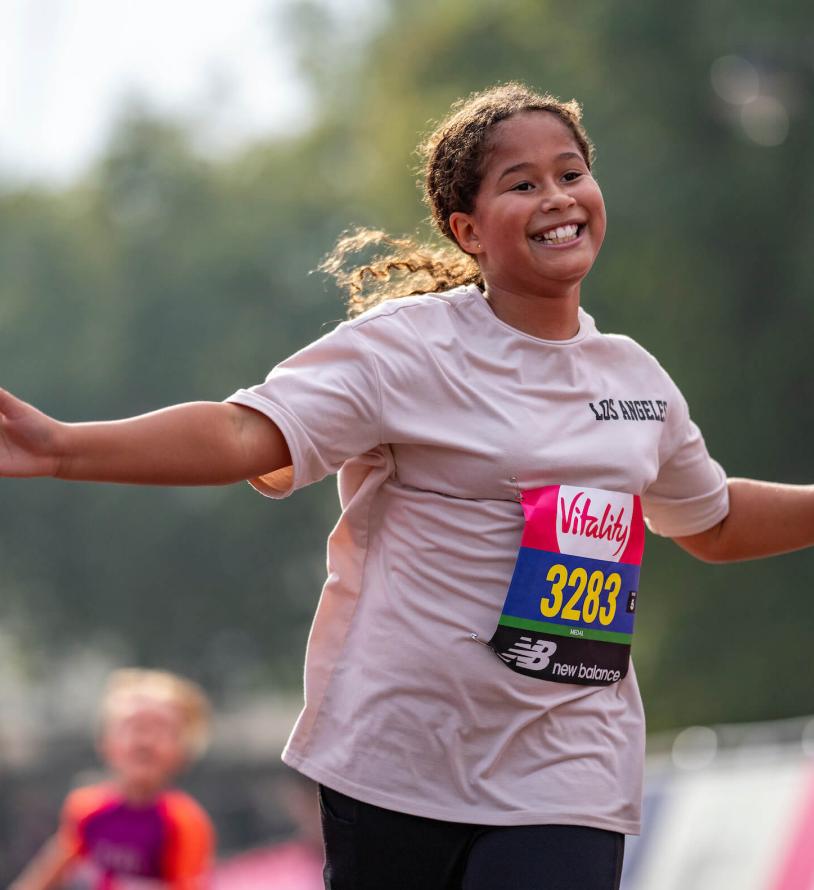 A young girl smiles with her hands out as she runs the Vitality Westminster Mile